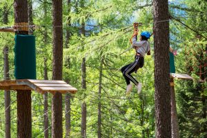 Avantura Park Zlatibor , pogled iz profila na osobu koja zasticena , visi na zip line izmedju drveca